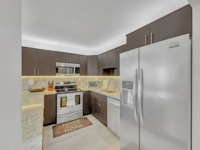 a kitchen with stainless steel appliances granite countertop a stove a sink dishwasher and a refrigerator