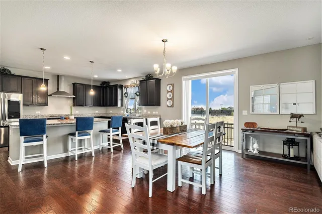 a kitchen with granite countertop a table chairs stainless steel appliances and wooden floor