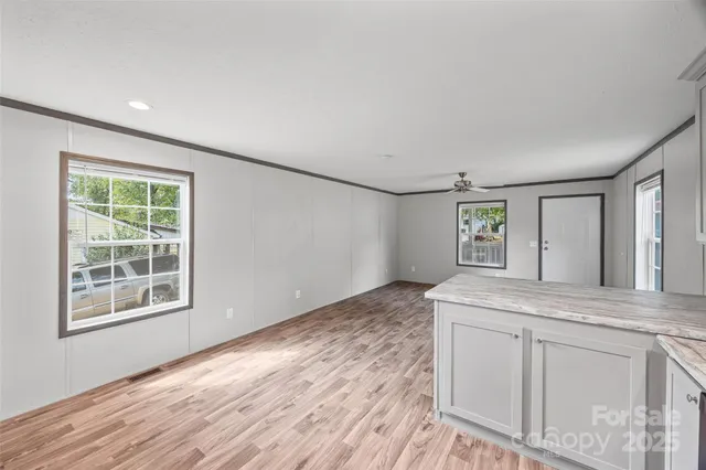 a view of an empty room with window and wooden floor
