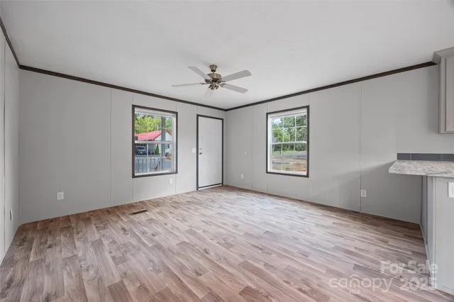 a view of an empty room with a window and a kitchen