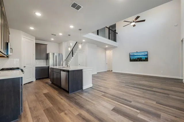 a kitchen with stainless steel appliances kitchen island wooden floors granite counter tops and a view of living room
