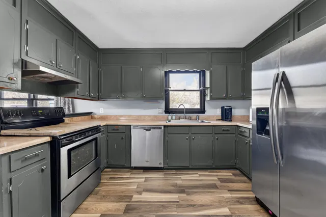 a kitchen with granite countertop a refrigerator a sink a stove and cabinets