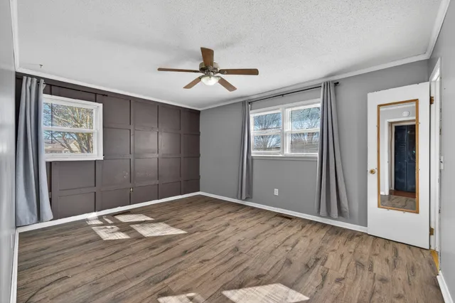 a view of empty room with wooden floor and ceiling fan