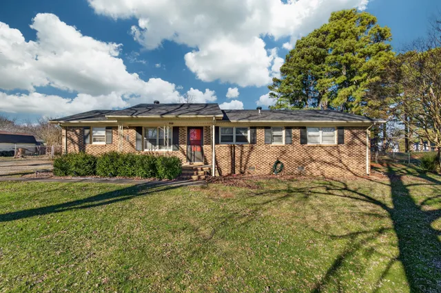 a view of a house with garden and a tree
