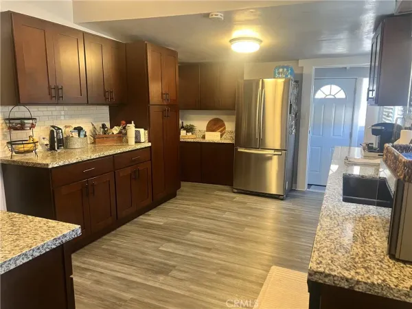 a kitchen with stainless steel appliances granite countertop a sink dishwasher stove and refrigerator with wooden floor