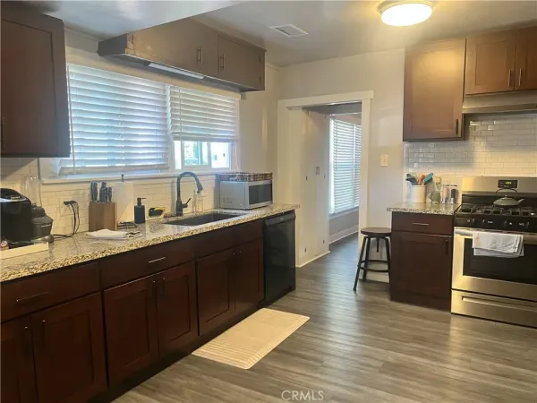 a kitchen with granite countertop a sink cabinets and wooden floor
