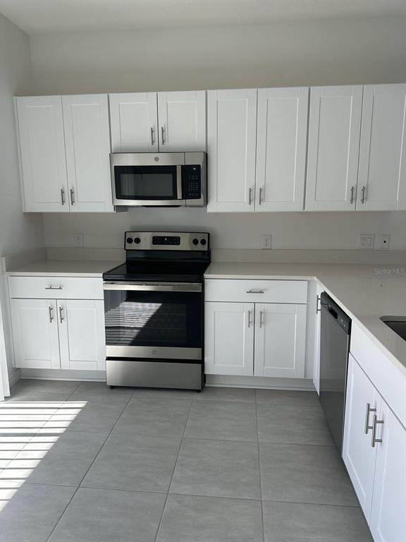 2084 Viewfinder Street Kissimmee, FL 34758 - Photo 5 of 18 a kitchen with white cabinets and appliances