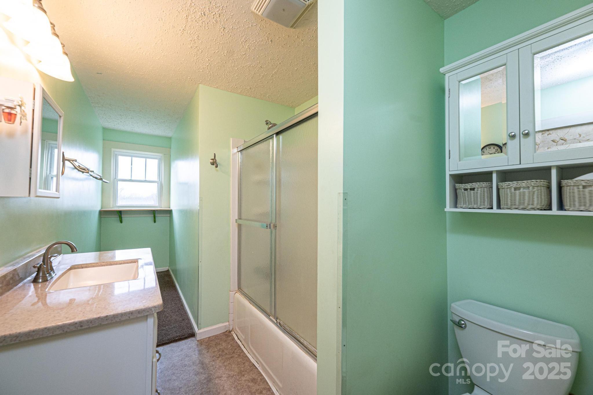 55 Duke Street Granite Falls, NC 28630 - Photo 24 of 45 a bathroom with a granite countertop sink a mirror and a toilet