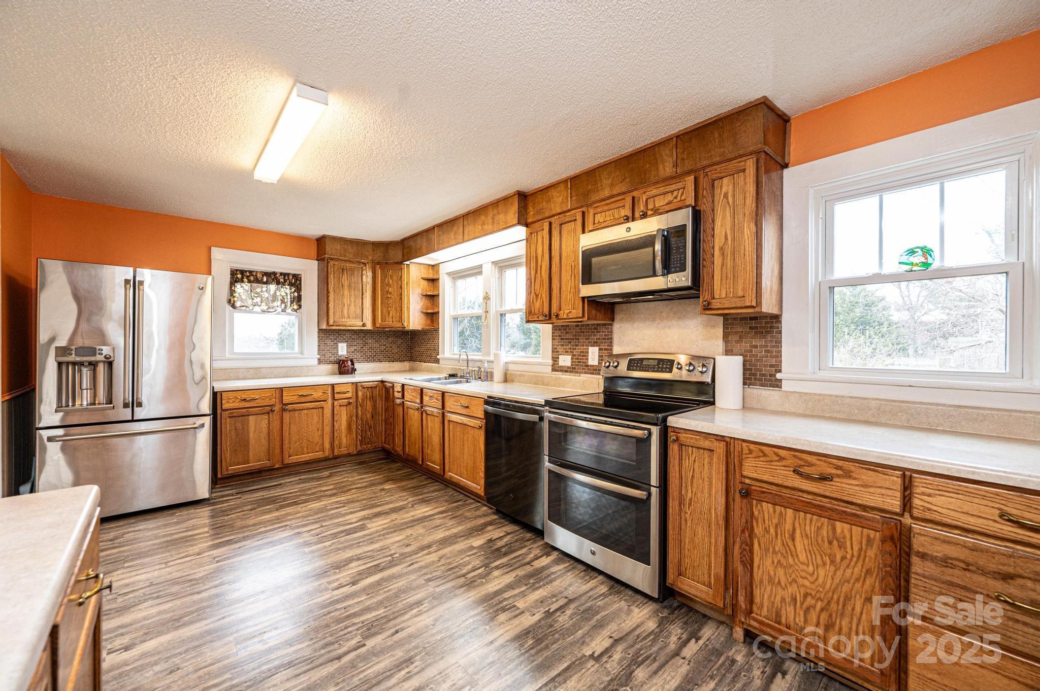 55 Duke Street Granite Falls, NC 28630 - Photo 10 of 45 a kitchen with stainless steel appliances granite countertop a stove top oven a sink dishwasher a refrigerator and cabinets with wooden floor