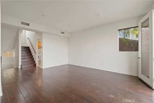 a view of an empty room with wooden floor and stairs