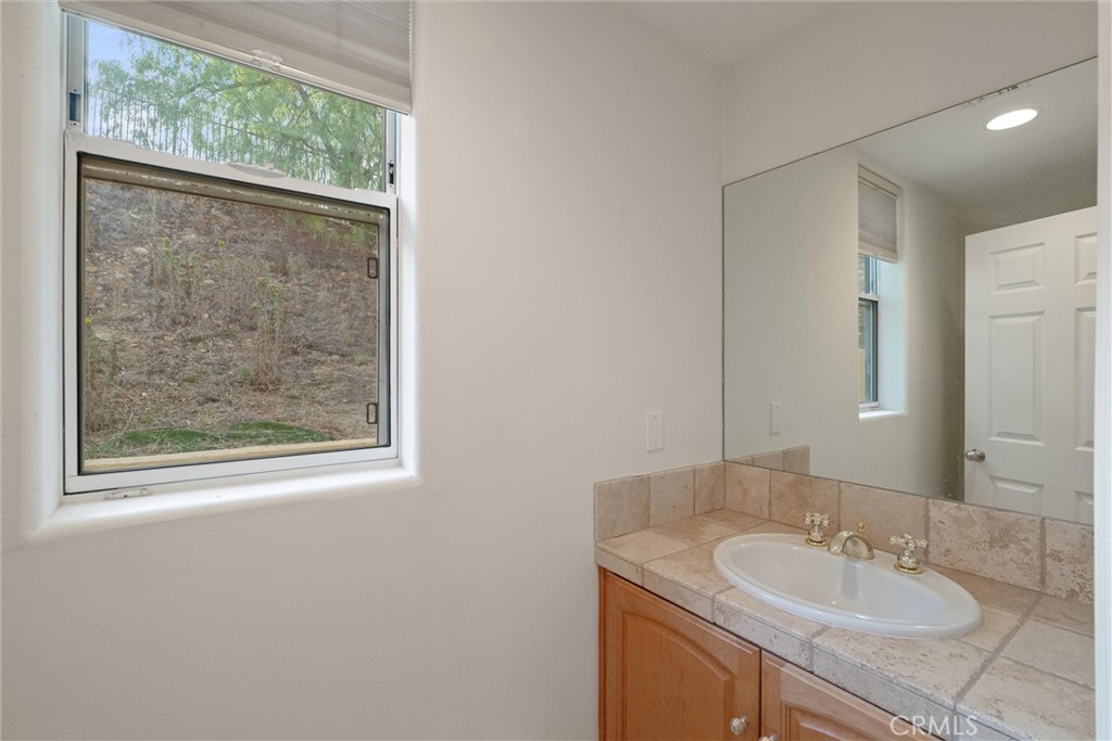 1259 Gonzales Road Simi Valley, CA 93063 - Photo 10 of 39 a bathroom with a granite countertop sink a mirror and a shower