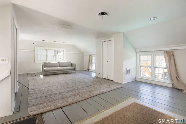 a view of kitchen and empty room with wooden floor