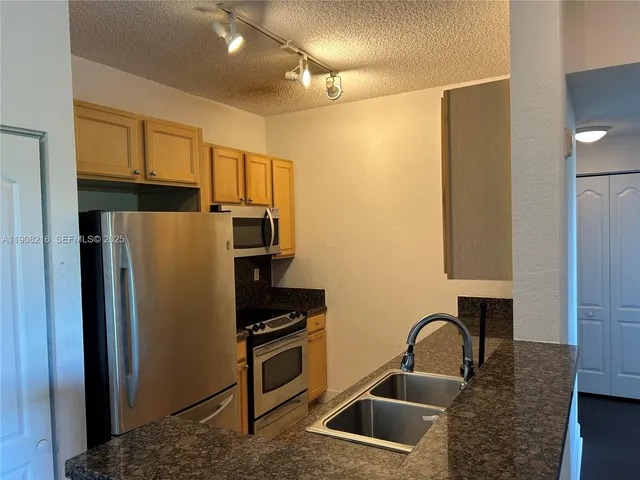 a kitchen with a refrigerator sink and cabinets