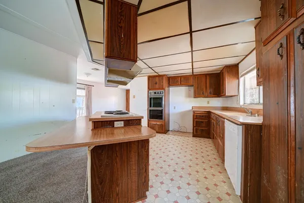 a kitchen with granite countertop a sink a stove top oven and cabinets