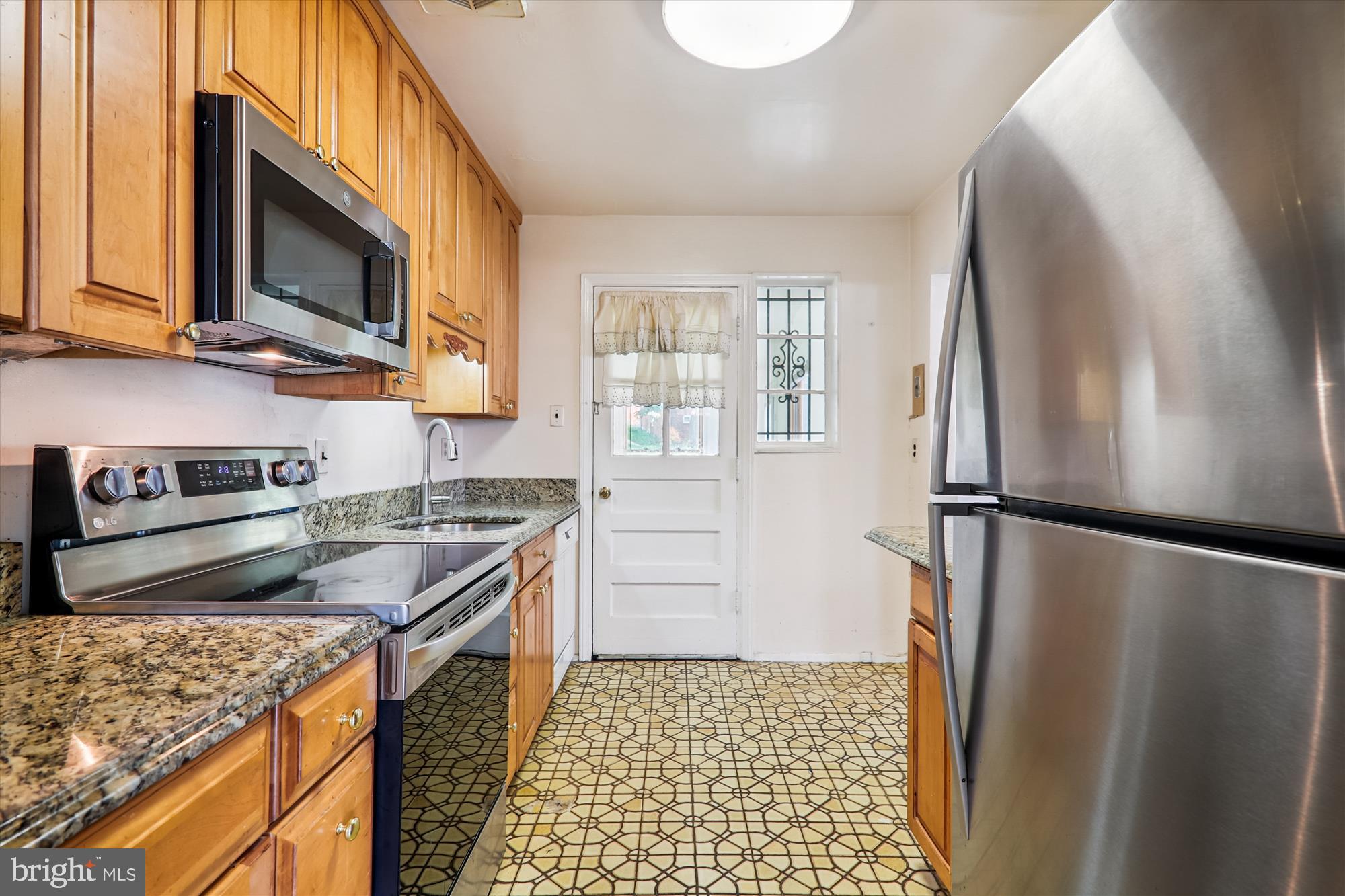 9507 Adelphi Road Silver Spring, MD 20903 - Photo 15 of 41 a kitchen with stainless steel appliances granite countertop a refrigerator a stove and a sink with wooden floor