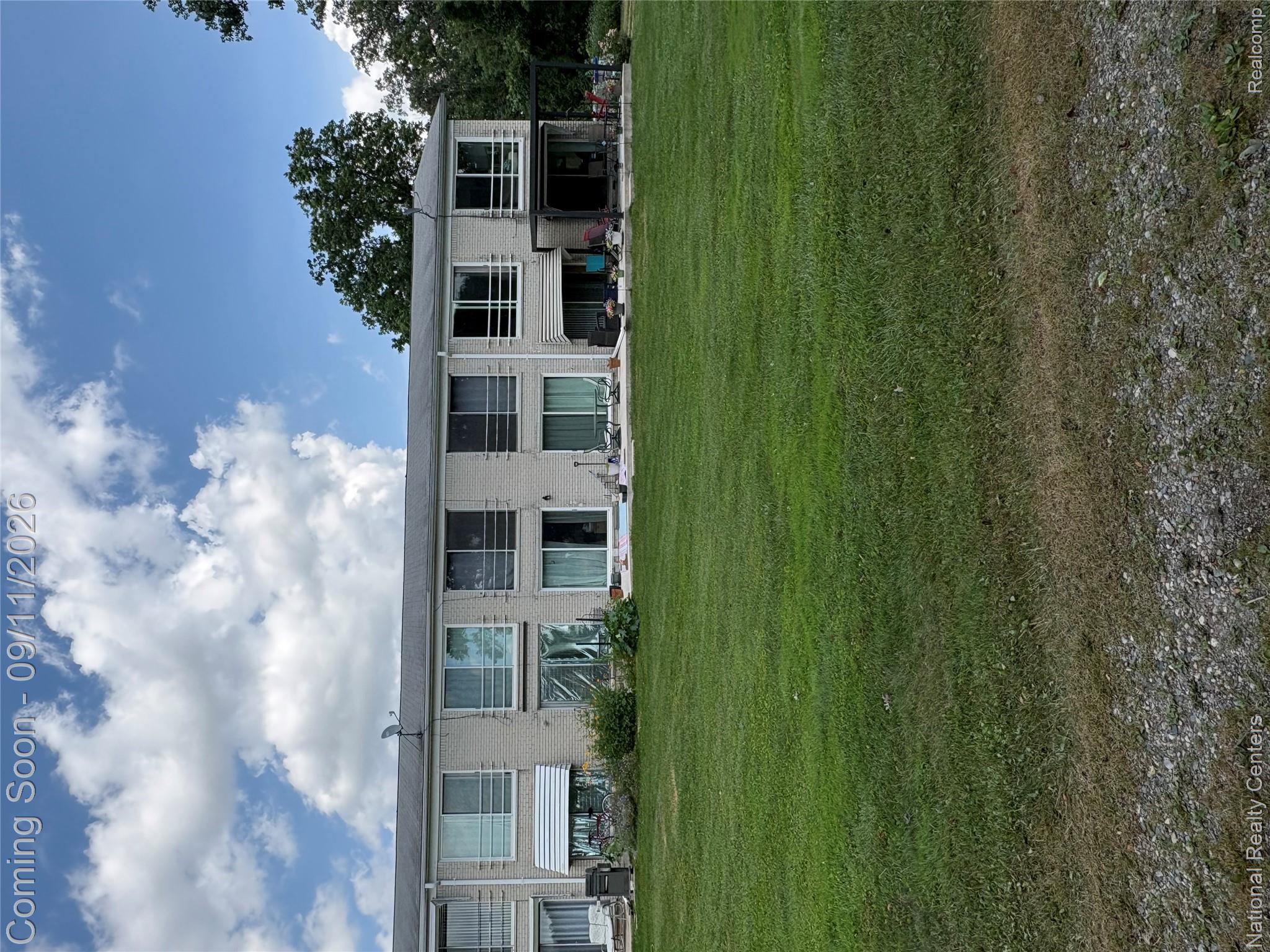 26945 Milford Road, Unit 3 New Hudson, MI 48165 - Photo 21 of 27 Two-story building featuring brick exterior, upper-level balconies with white railings, and ground-level patios with sliding glass doors
