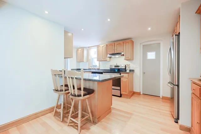 a kitchen with stainless steel appliances granite countertop a stove top oven a sink dishwasher and white cabinets with wooden floor