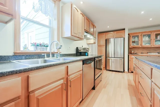 a kitchen with stainless steel appliances granite countertop a refrigerator a sink a stove and island with wooden floor