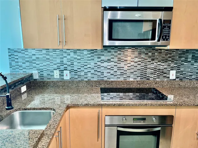 a kitchen with stainless steel appliances granite countertop a refrigerator a stove a sink and a counter space