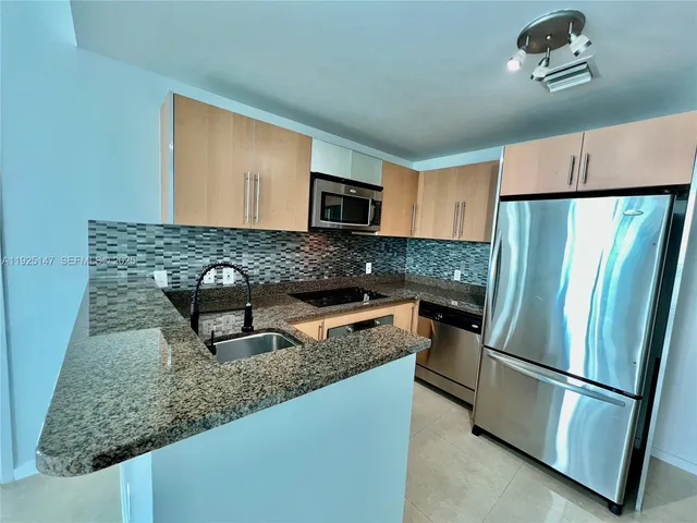 a kitchen with granite countertop a sink stove and refrigerator