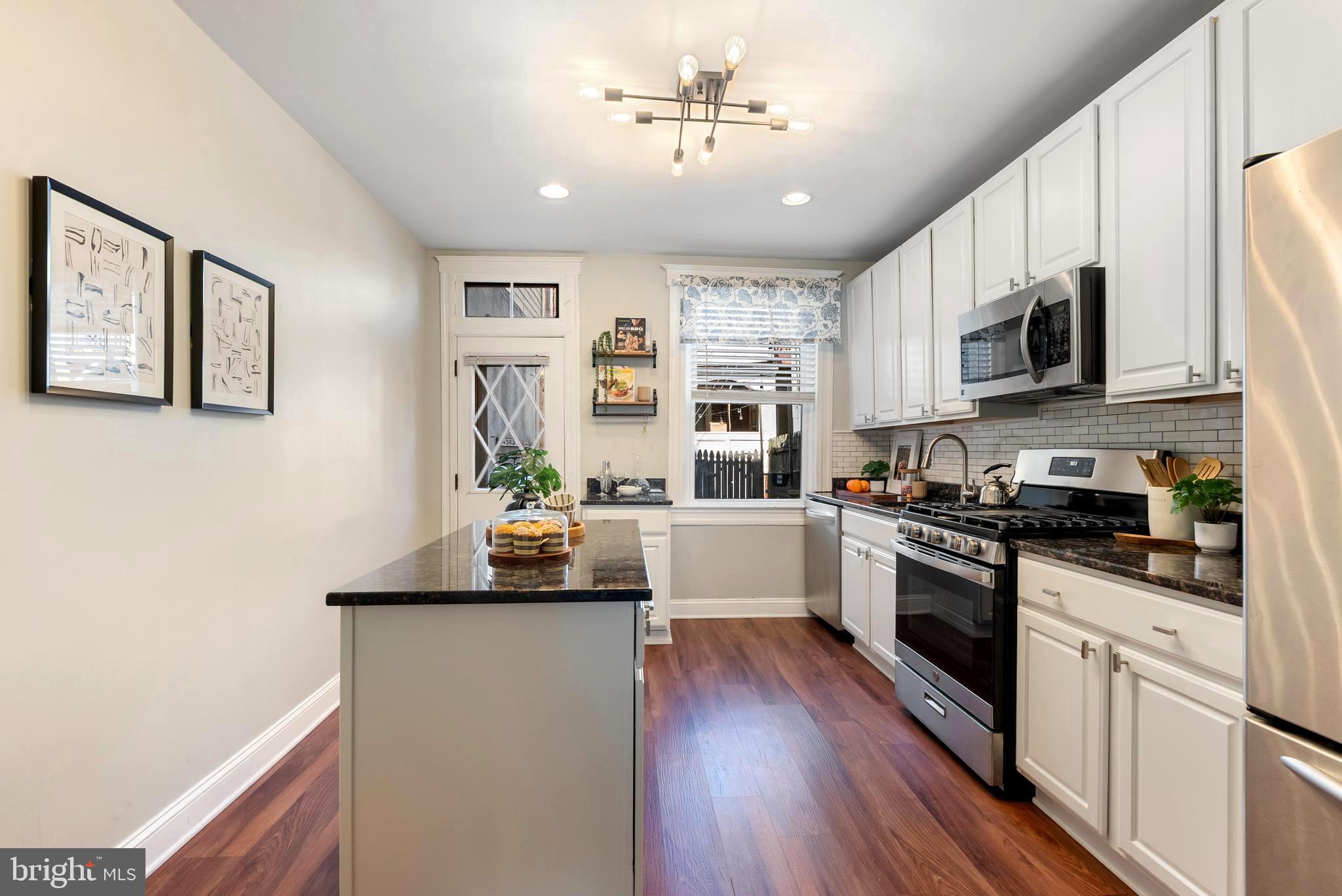 280 South Robinson Street Baltimore, MD 21224 - Photo 12 of 40 a kitchen with stainless steel appliances granite countertop a sink a stove top oven a counter space and cabinets