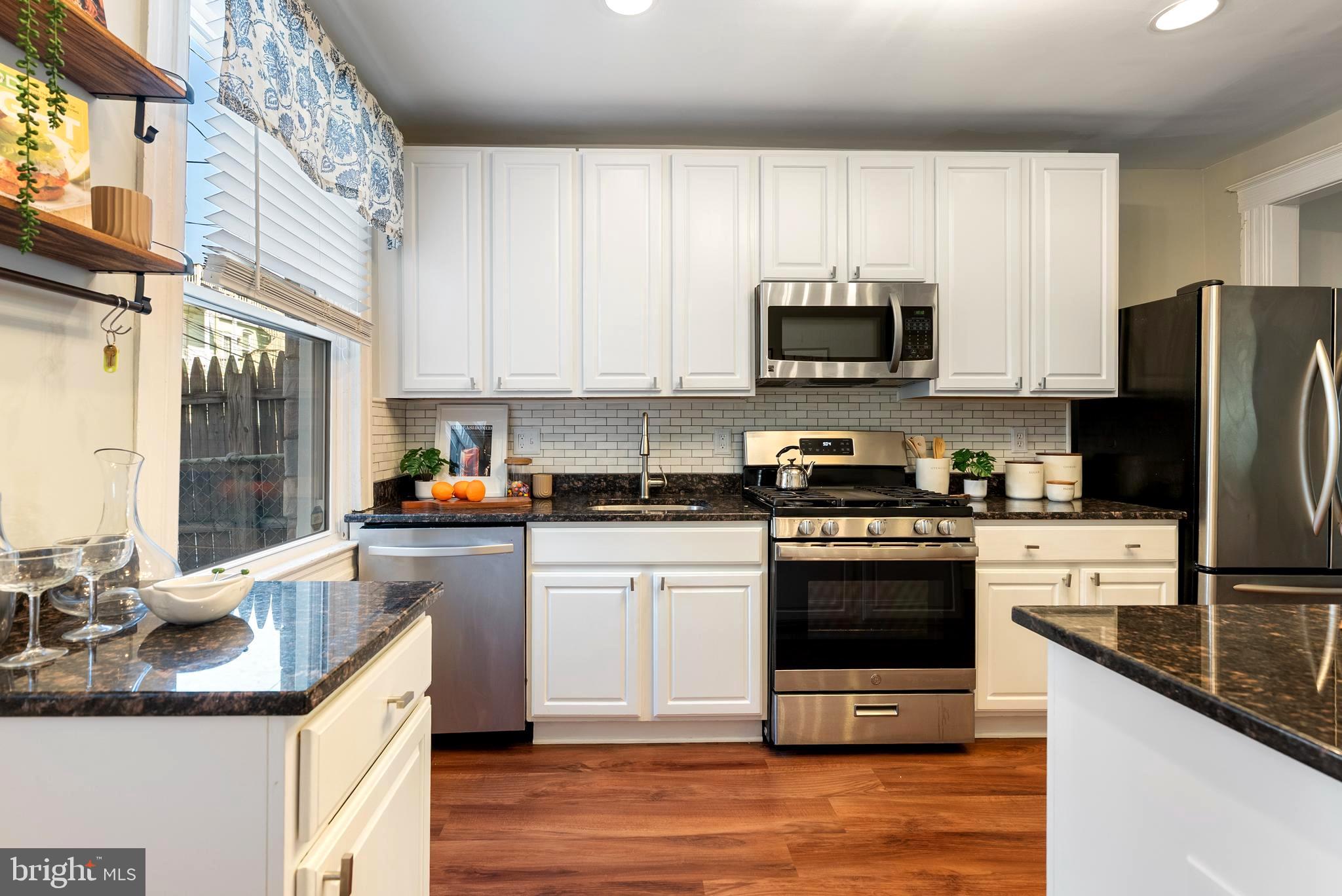280 South Robinson Street Baltimore, MD 21224 - Photo 14 of 40 a kitchen with stainless steel appliances granite countertop a stove top oven a sink dishwasher a refrigerator and a microwave oven with wooden floor