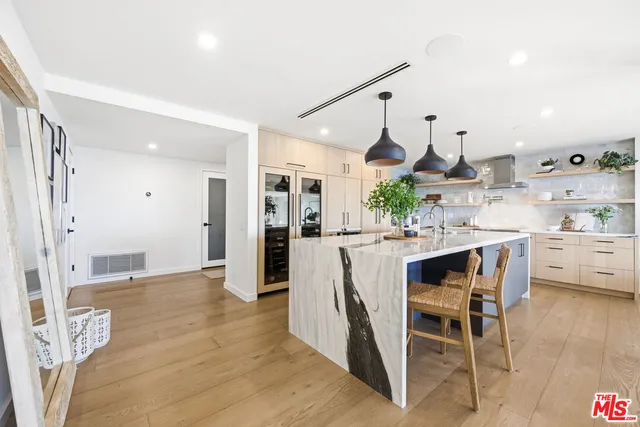 a kitchen with stainless steel appliances kitchen island granite countertop a table chairs and a refrigerator