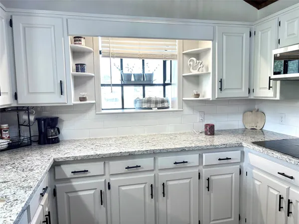 a kitchen with granite countertop white cabinets and white stainless steel appliances