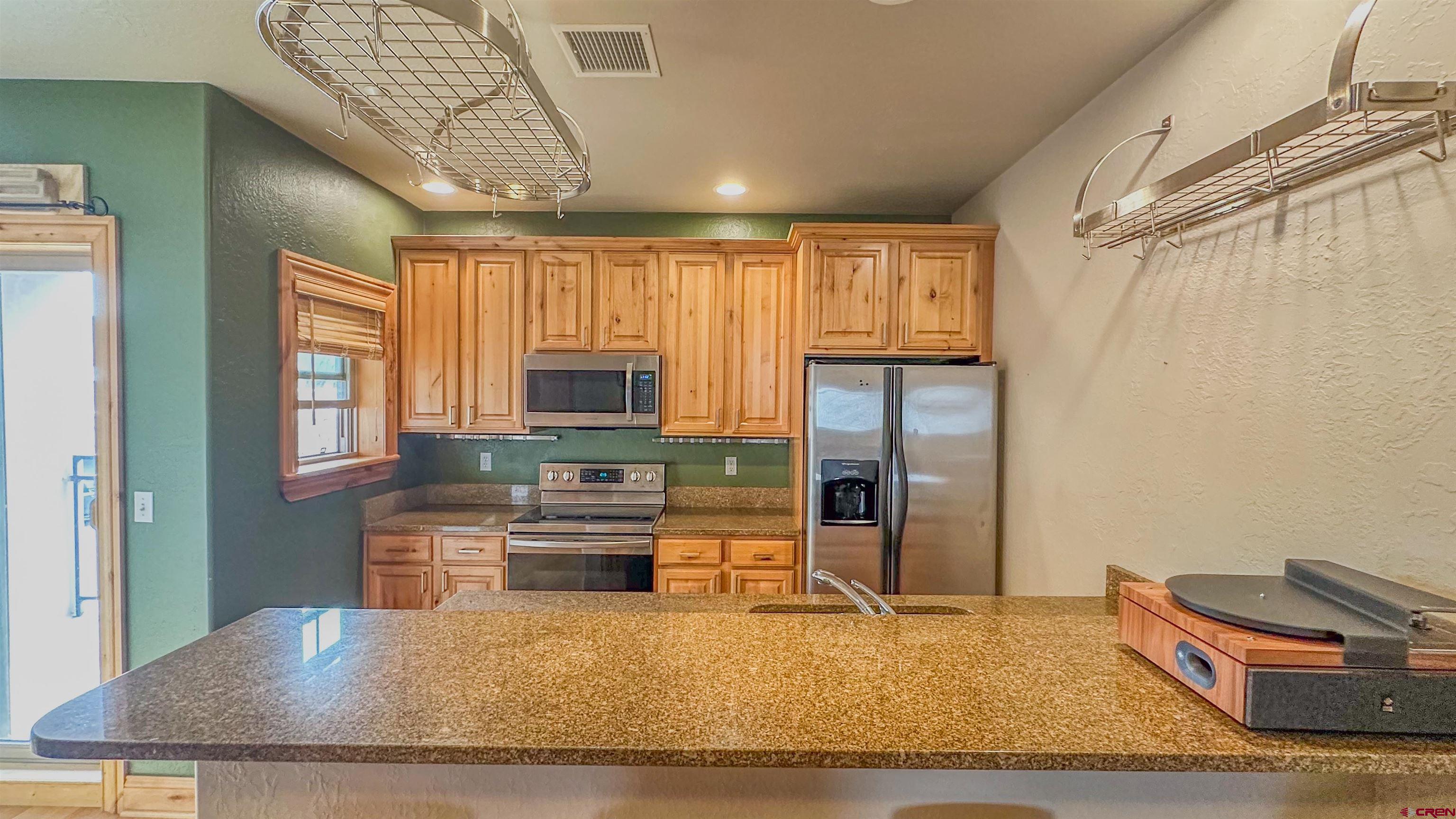 2855 Main Avenue, Unit A 209 Durango, CO 81301 - Photo 9 of 20 a kitchen with stainless steel appliances granite countertop a refrigerator a stove and a sink with wooden cabinets