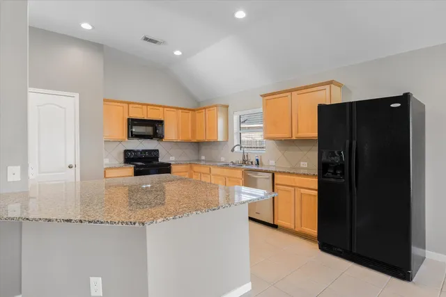 a kitchen with granite countertop a refrigerator and a stove top oven