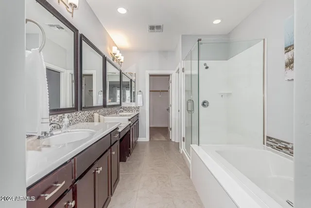 a spacious bathroom with a granite countertop tub a double vanity sink a large mirror and a shower