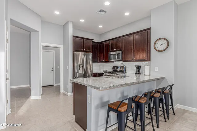a kitchen with stainless steel appliances granite countertop a table chairs sink and refrigerator