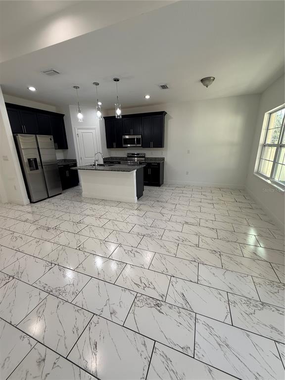2314 Apache Avenue Kissimmee, FL 34744 - Photo 12 of 29 a kitchen with stainless steel appliances kitchen island granite countertop a rug and white cabinets