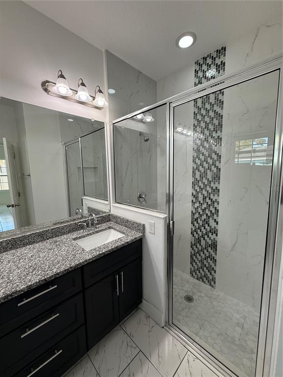 2314 Apache Avenue Kissimmee, FL 34744 - Photo 20 of 29 a bathroom with a granite countertop sink a large mirror and a shower