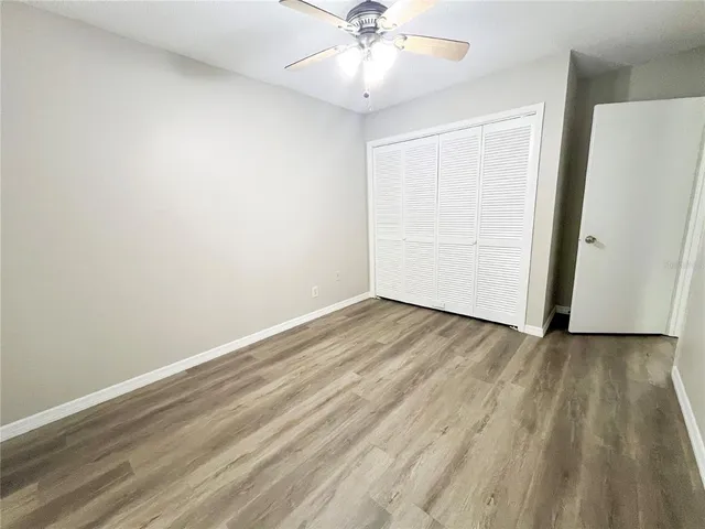 an empty room with wooden floor closet and ceiling fan