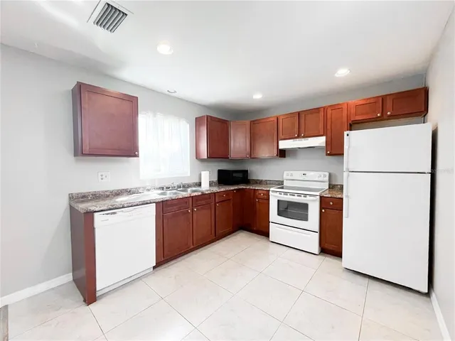 a kitchen with granite countertop a refrigerator and a stove top oven
