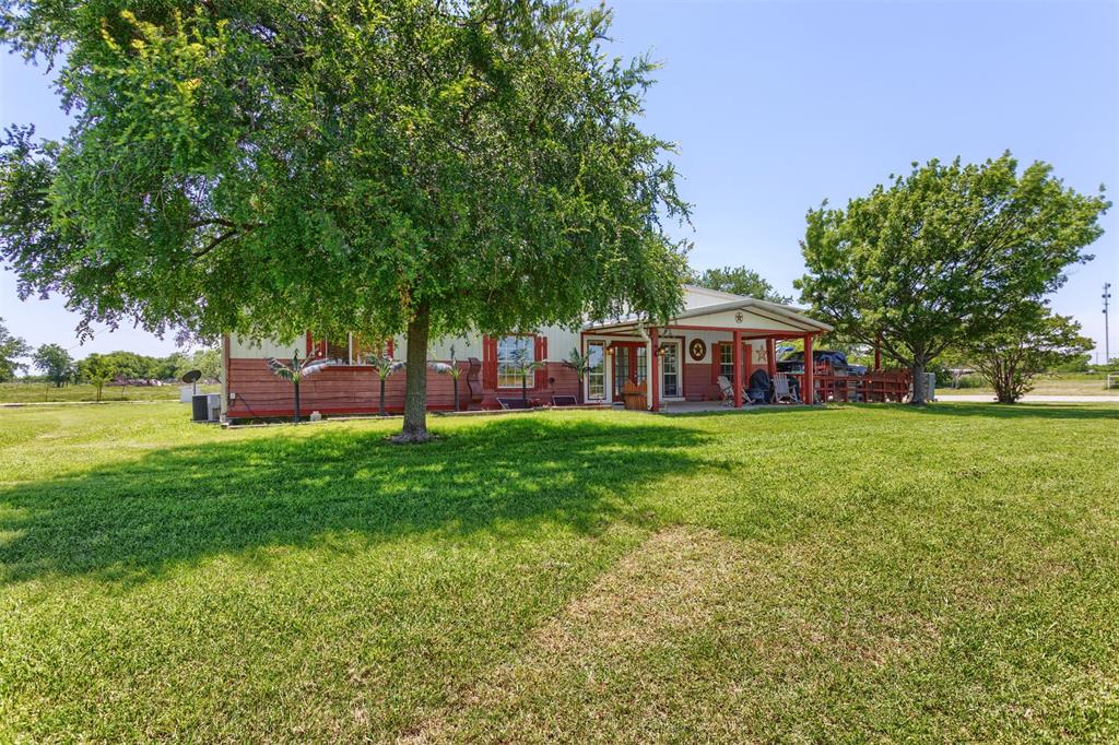 View of grassy yard featuring covered porch