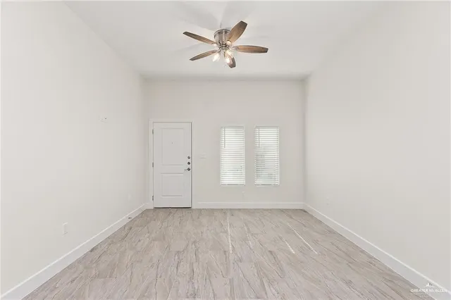 an empty room with wooden floor and ceiling fan