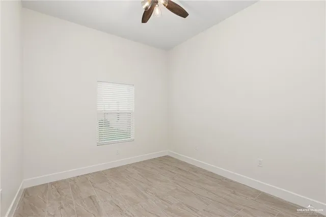 an empty room with ceiling fan and window