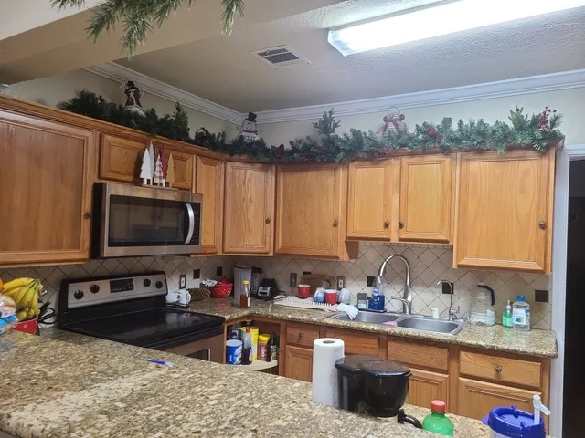 a kitchen with stainless steel appliances granite countertop a stove a sink dishwasher and a microwave with wooden cabinets