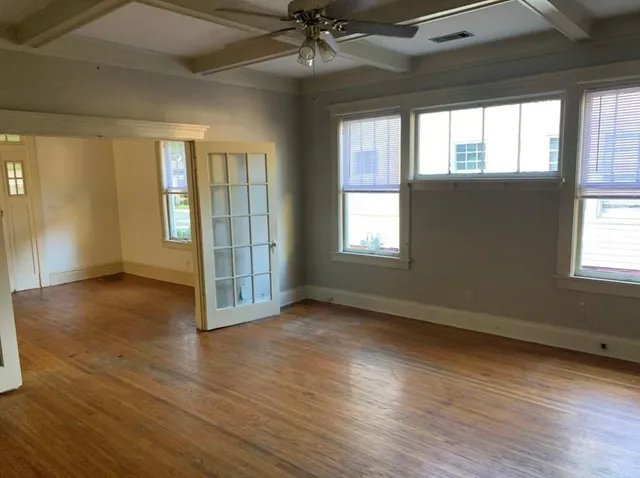 an empty room with wooden floor and windows