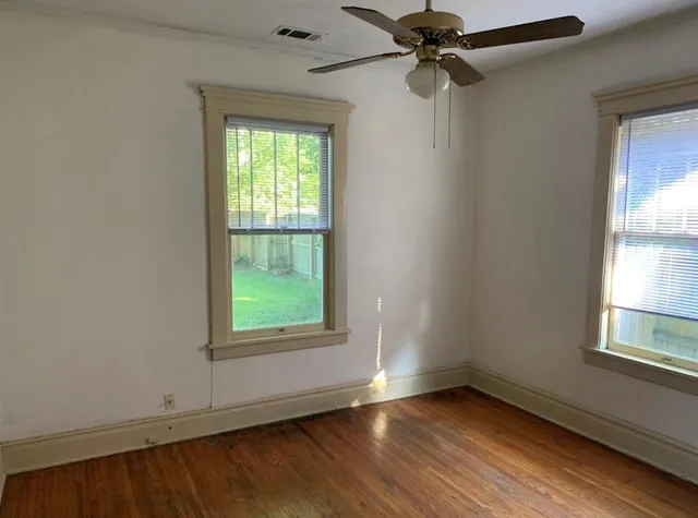 an empty room with windows and fan