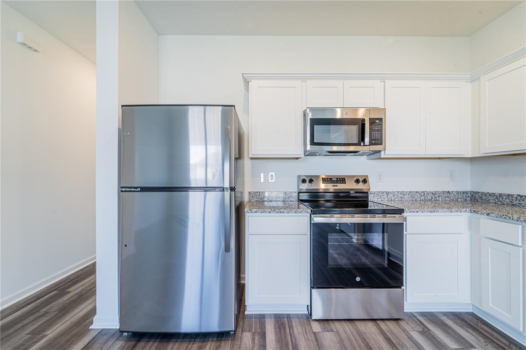 6174 Daerr Rdg Street Zephyrhills, FL 33542 - Photo 29 of 41 a kitchen with a refrigerator and a stove top oven