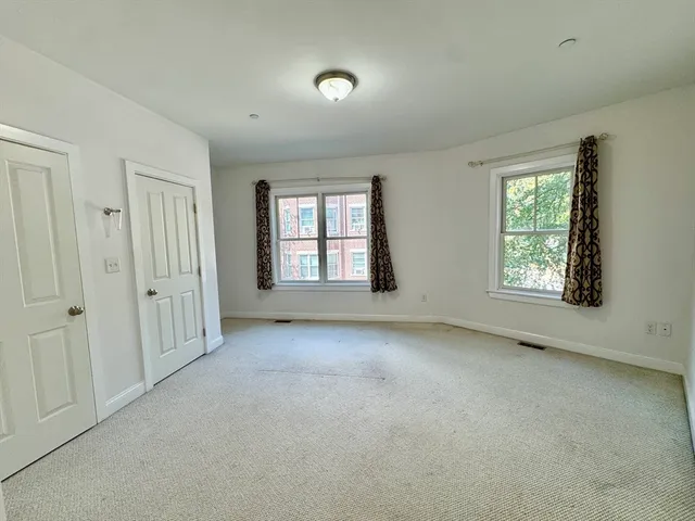 an empty room with windows and closet area