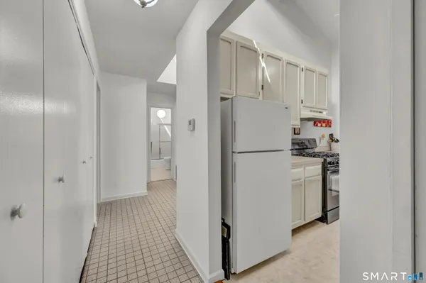 a view of hallway with refrigerator and wooden floor
