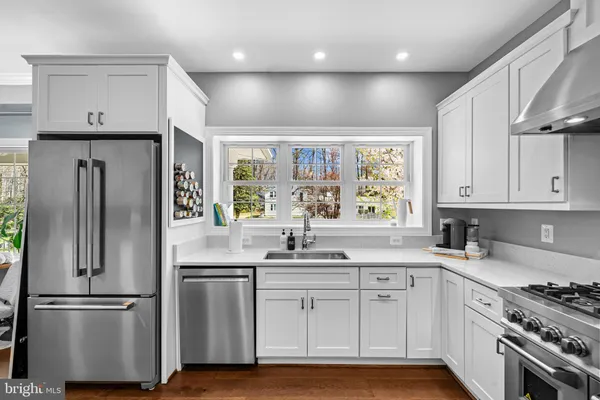 a kitchen with stainless steel appliances granite countertop a stove a refrigerator a kitchen island a sink white cabinets and chairs