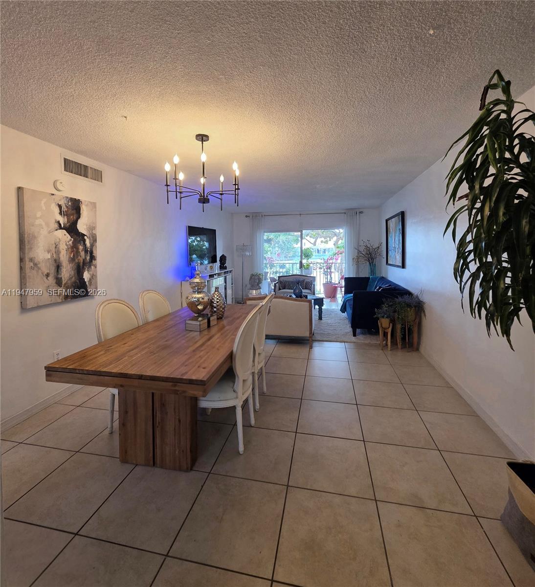 7424 Southwest 82nd Street, Unit D215 Miami, FL 33143 - Photo 12 of 33 a living room with furniture a chandelier and a dining table