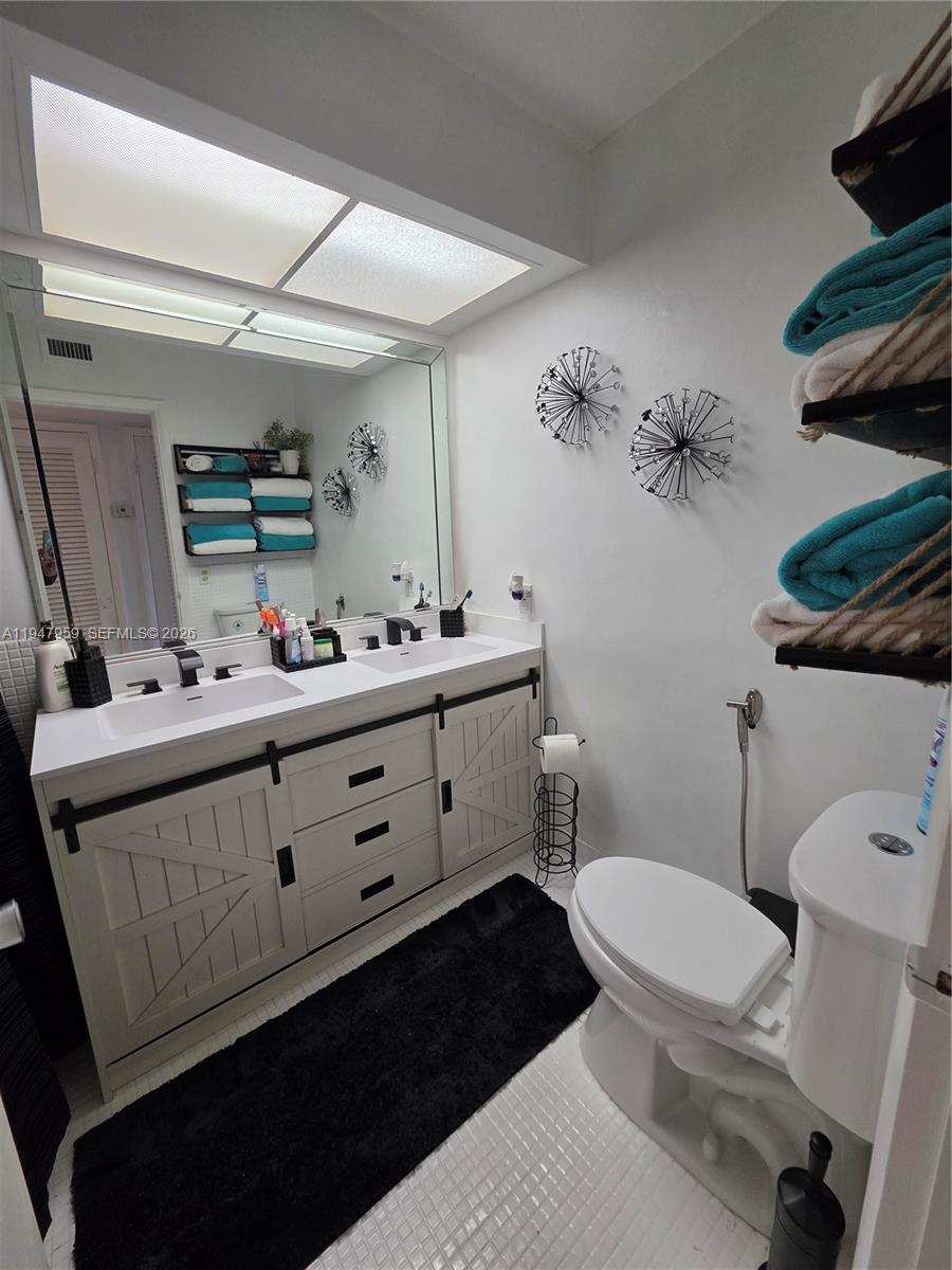7424 Southwest 82nd Street, Unit D215 Miami, FL 33143 - Photo 22 of 33 a bathroom with a sink mirror and toilet