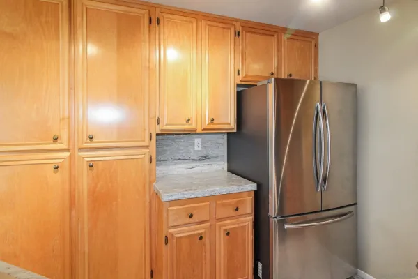 a view of a refrigerator in kitchen and white cabinets