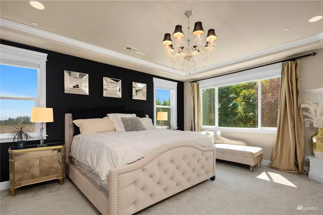 a bedroom with a large bed a chandelier and a flat screen tv